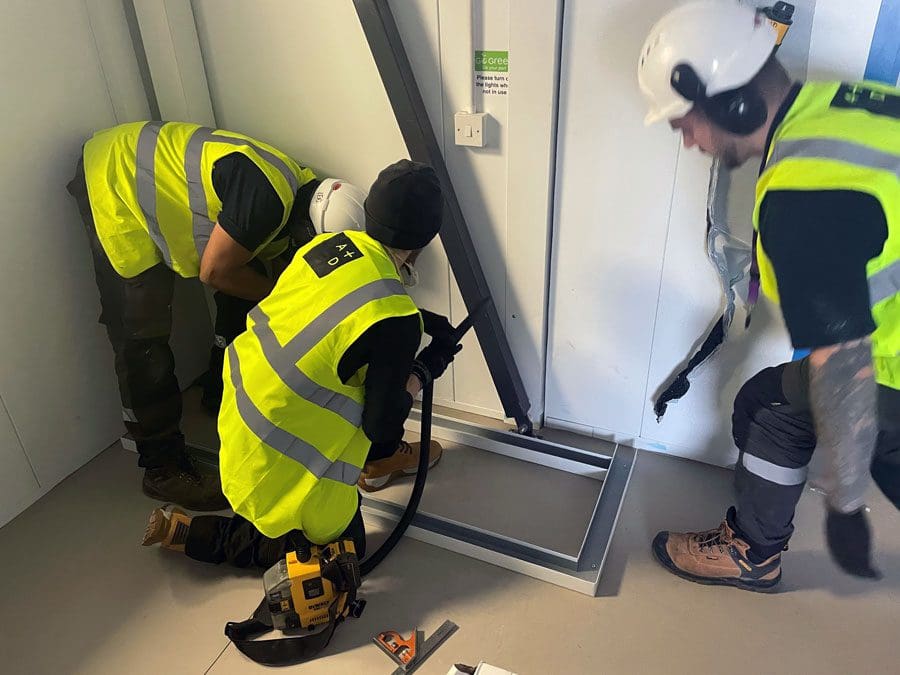 3 men in high visibility jackets installing some equipment to cleanrooms